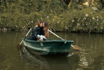 Sensual couple embracing on boat at lake over bushes on background — Stock Photo