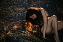 Веселая молодая девушка в шортах позирует на земле в лучах заката — стоковое фото