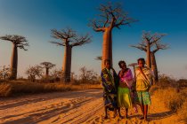 Persone locali in piedi davanti agli alberi di baobab, Madagascar, Africa — Foto stock