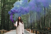 Mujer caminando con antorcha de humo púrpura - foto de stock
