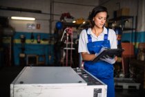 Жінка-механік за допомогою планшетного комп'ютера в гаражі — стокове фото