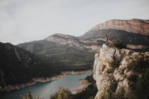 Віддалений вид на пішохода, що стоїть на скелі на тлі красивого гірського пейзажу — стокове фото
