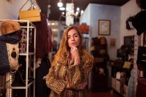 Young stylish girl in posing in fur coat on background of clothing room. — Stock Photo