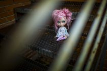 Vista obcecada da boneca de cabelos cor-de-rosa sentada nas escadas — Fotografia de Stock