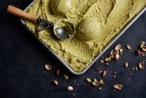 From above container of pistachio ice-cream and scoop — Stock Photo