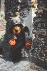 Девушка в шапке ведьмы позирует у каменной стены — стоковое фото