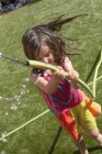 Menina brincando com mangueira no gramado no dia quente de verão — Fotografia de Stock