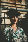 Espressiva ragazza con afro posa alla luce del sole sopra parete industriale — Foto stock