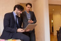 Due giovani colleghi in abiti formali guardando laptop in ufficio . — Foto stock