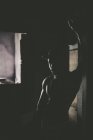 Retrato do homem muscular posando em quarto escuro e inclinando-se na parede . — Fotografia de Stock