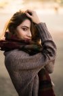 Side view of woman dressed in warm clothes holding her hair and looking at camera. — Stock Photo