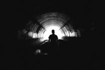 Обратный вид неизвестного человека, стоящего глубоко в туннеле . — стоковое фото