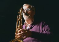 Зрелый мужчина играет на саксофоне с закрытыми глазами — стоковое фото