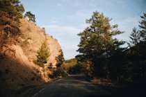Деревенская дорога бежит вдоль залитых солнцем скал — стоковое фото