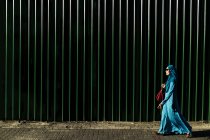 Каула-Лумпур, Malasia - 28 Mart, 2016: Боковим видом жінки носять синій Абая та хустку ходьба alongmetal огорожі. — стокове фото