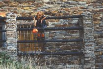 Дівчина з гарбузовим кошиком позує на паркані — стокове фото