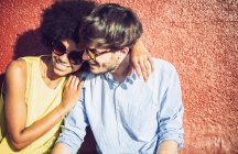 Interracial couple embracing by red wall — Stock Photo
