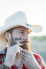 Портрет бородатого человека в ковбойской шляпе, бреющегося винтажной бритвой и выглядящего офигенно — стоковое фото
