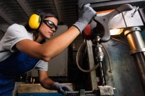 Low angle view of female mechanic operating column type drill — Stock Photo