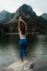 Жінка позує на камені на гірському озері — стокове фото