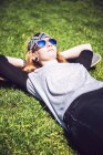 Jeune femme reposant sur planche à roulettes sur herbe — Photo de stock