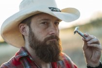 Ritratto di uomo barbuto in cappello da cowboy rasatura con rasoio vintage a doppio taglio — Foto stock