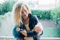 Portrait of blond woman posing with dolls and looking at them — Stock Photo