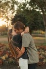 Portrait of young embracing couple kissing at park — Stock Photo