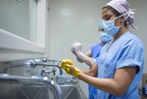 Побочный обзор врачей в униформе, моющих руки перед операцией — стоковое фото