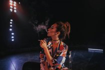Femme tenant cigarette expirant fumée — Photo de stock