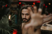Portrait of man with dreadlocks posing without shirt outstretching hand at camera — Stock Photo