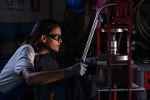 Side view of female mechanic in protective googles operating hydraulic press — Stock Photo