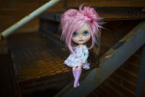 Vista da vicino della bambola moderna dai capelli rosa seduta sulle scale — Foto stock