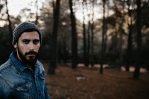 Homem barbudo andando na floresta e olhando para a câmera — Fotografia de Stock