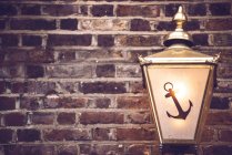Textured background of crop brick wall decorated with antique lantern with anchor symbol — Stock Photo