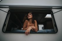 Woman in lace bra looking out of trailer window — Stock Photo