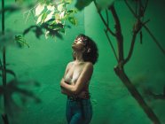 Брюнетка дівчина в бюстгальтері позує з закритими очима над зеленою стіною — стокове фото