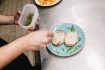 Над видом мужской руки кладет нарезанную петрушку на голубую тарелку с блюдом — стоковое фото