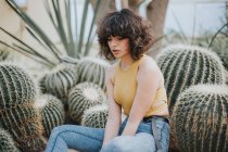 Bruna ragazza seduta da cactus e guardando giù — Foto stock