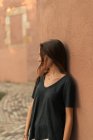 Porträt eines brünetten Mädchens, das sich an die Wand lehnt und wegschaut — Stockfoto