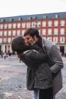Молодая пара целует друг друга на городской площади — стоковое фото