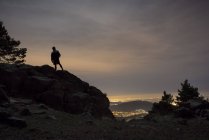 Silhouette de l'homme au sommet de la montagne contre le ciel du crépuscule — Photo de stock