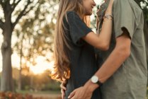 Crop image of boy embracing girl at park on sunset — Stock Photo