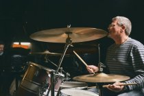 Side view of mature man playing drums — Stock Photo