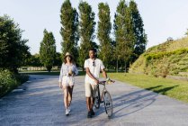 Casal com bebidas e bicicleta no parque urbano — Fotografia de Stock