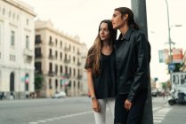 Портрет обнимающей пары, опирающейся на столб на улице — стоковое фото
