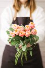 Primo piano di fiorista femminile che tiene mazzo di rose rosa fresche — Foto stock
