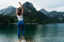 Женщина позирует на камне у горного озера — стоковое фото
