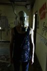 Homme en masque à gaz marchant dans une maison abandonnée — Photo de stock