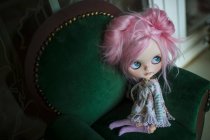 Vista de cerca de la muñeca moderna de pelo rosa sentada en sillones pequeños - foto de stock